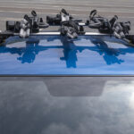 3 Bicycle Racks Mounted On Blue Car Roof.